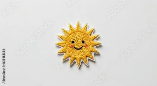 Obraz Yellow embroidered sun patch on white surface. Soft lighting shows clean texture, ideal for product design, clothing mockups, branding.