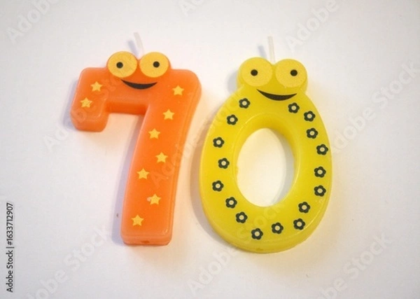 Fototapeta Close-up of a birthday candle in the shape of number 70 on a clean white background. Isolated with space for text.