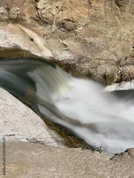 Obraz A Long-Exposed Waterfall through Rock