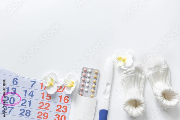 Fototapeta Pregnancy planning. Pregnancy test, calendar and booties on white background top view copyspace
