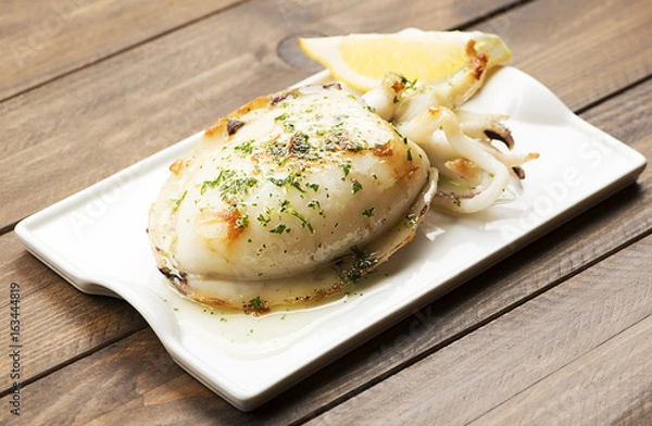 Fototapeta Close-up of cuttlefish with garlic and parsley and lemon on wooden table.