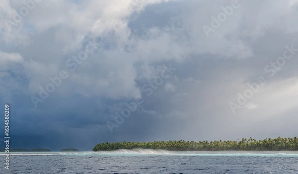 Fototapeta Storm approaching an atoll as waves crash on the reef barrier