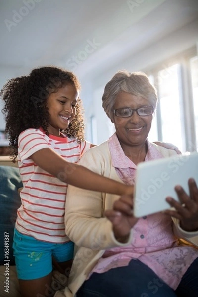 Obraz Grandmother and granddaughter using tablet 