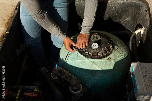 Fototapeta Hombre reparando el filtro de la depuradora de una piscina.