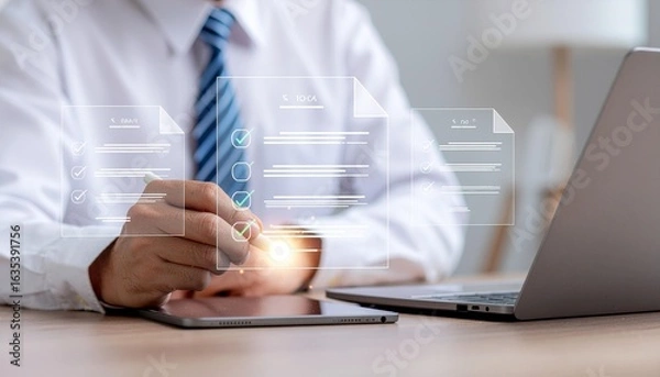 Fototapeta Businessman completing digital checklist on tablet with laptop for modern business workflow success