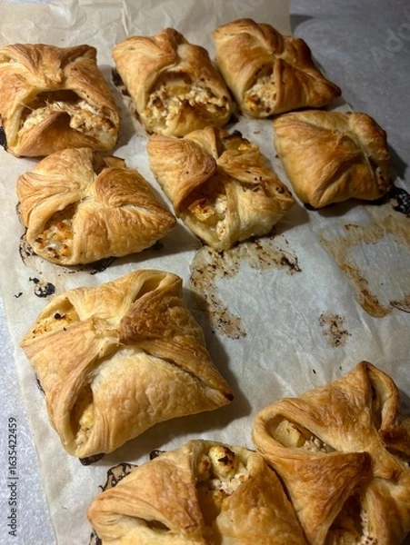 Fototapeta Homemade puff pastry pies with cheese filling on baking paper top view. 