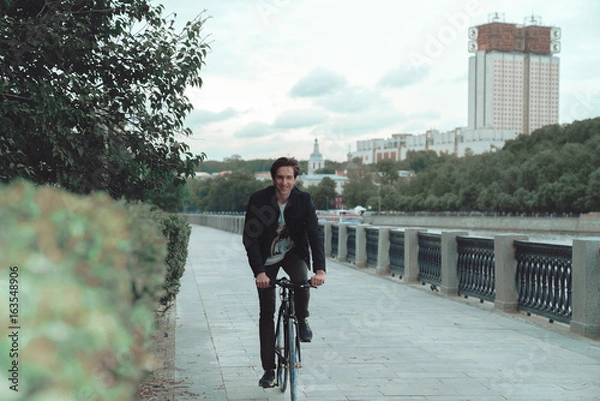 Obraz A man is riding a bicycle in a park on the waterfront