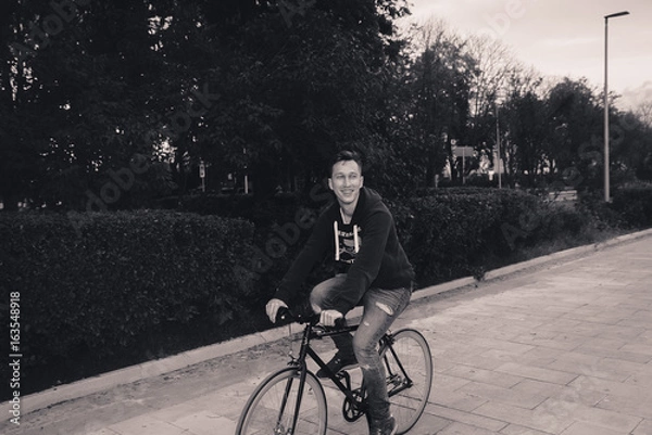 Obraz A man is riding a bicycle in a park on the waterfront