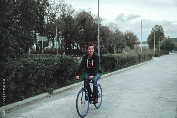 Obraz A man is riding a bicycle in a park on the waterfront