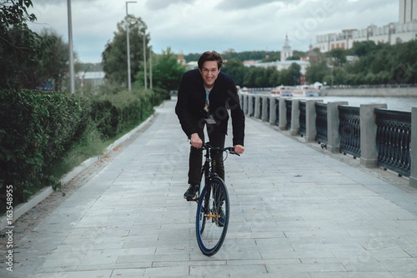 Obraz A man is riding a bicycle in a park on the waterfront