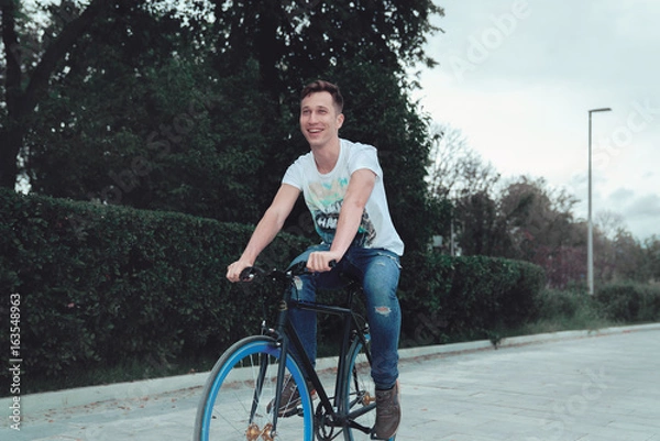 Obraz A man is riding a bicycle in a park on the waterfront