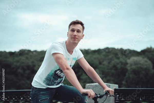 Obraz A man is riding a bicycle in a park on the waterfront