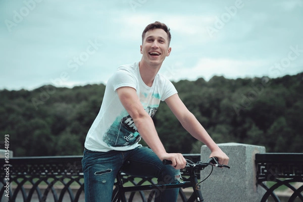 Obraz A man is riding a bicycle in a park on the waterfront