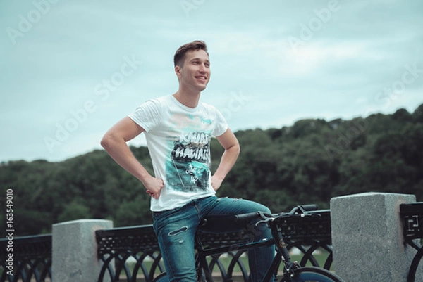 Obraz A man is riding a bicycle in a park on the waterfront