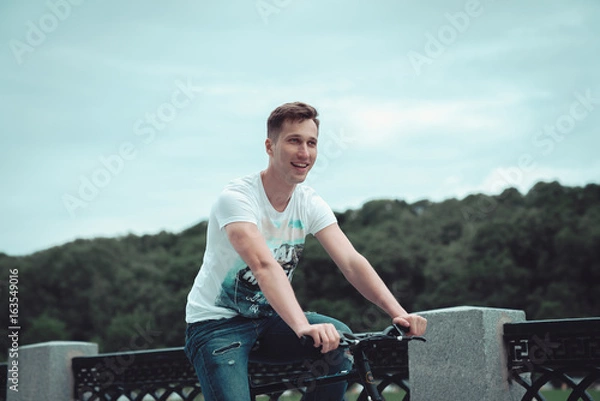 Obraz A man is riding a bicycle in a park on the waterfront