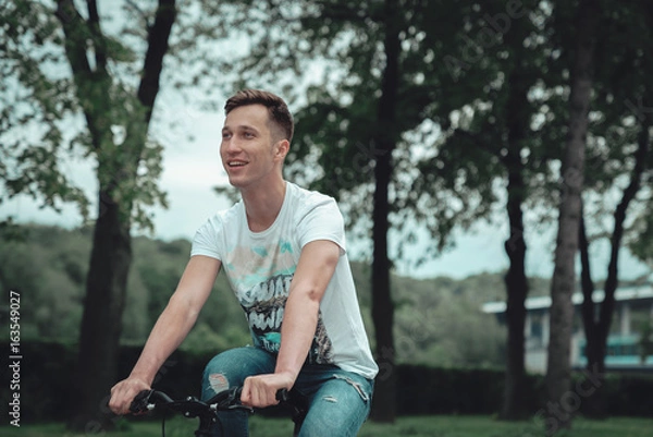 Obraz A man is riding a bicycle in a park on the waterfront