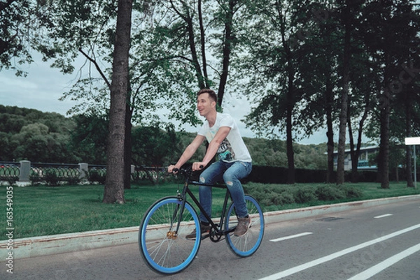 Obraz A man is riding a bicycle in a park on the waterfront