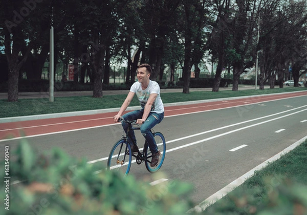 Obraz A man is riding a bicycle in a park on the waterfront