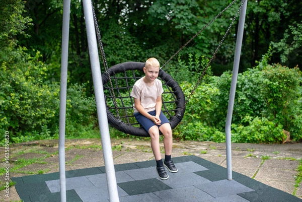 Fototapeta Smiling boy on swing - real-life emotion in the park.