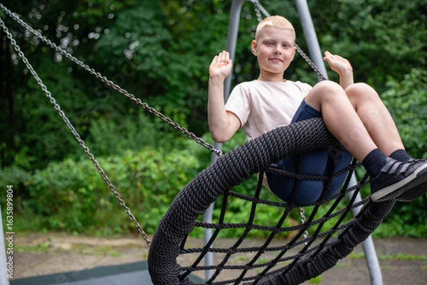 Fototapeta Smiling boy on swing - real-life emotion in the park.