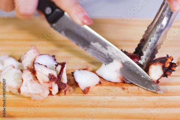 Fototapeta Using knife to cut octopus on cutting board