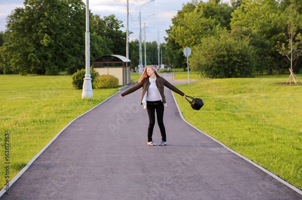 Fototapeta A young girl is spinning in the park for joy