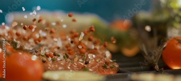 Fototapeta Seasoning falling on hamburger meat grilling with vegetables and tomatoes