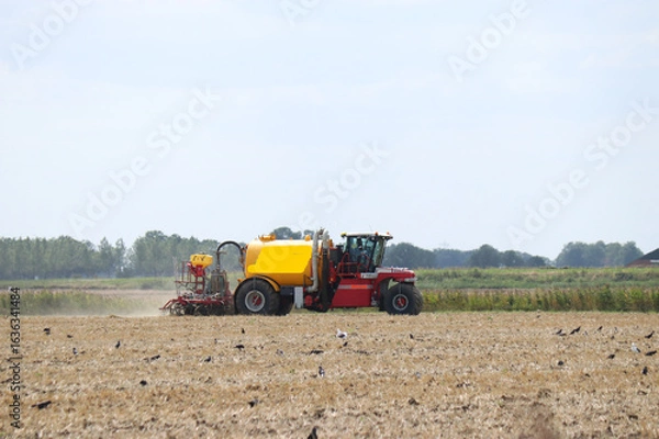 Fototapeta a hydro trike is fertilizing a bare field with slurry in the countryside in summer