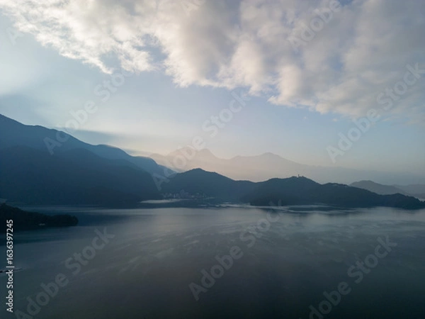 Obraz Aerial view of a serene lake reflecting mountains and clouds at sunrise. Misty atmosphere.
