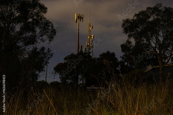Fototapeta Telecommunications tower illuminated at night with starry background