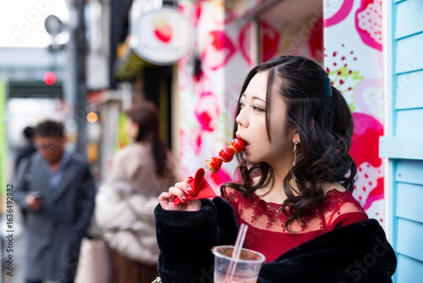 Fototapeta 都会の路地でいちご飴を食べる日本人女性のポートレート