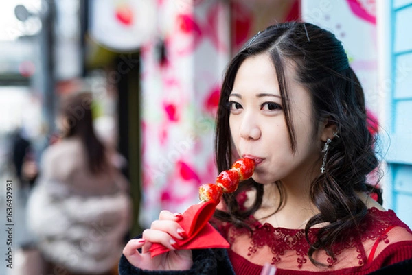 Obraz 都会の路地でいちご飴を食べる日本人女性のポートレート