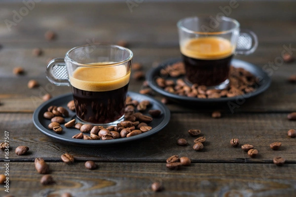 Obraz Two cups of espresso and coffee beans on a wooden table