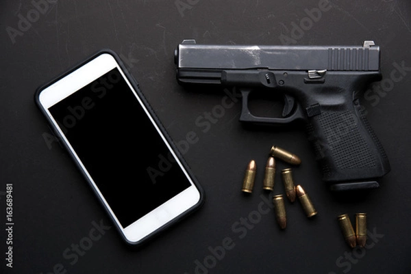 Fototapeta Gun with ammunition and mobile phone on black background. top view