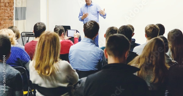 Obraz Dorośli studenci słuchają wykładu profesora w małej sali. Panoramiczny współczynnik kształtu.