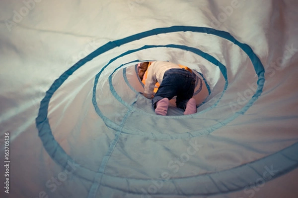 Obraz a little boy developing lessons for toddlers crawling through the "tube" tunnel