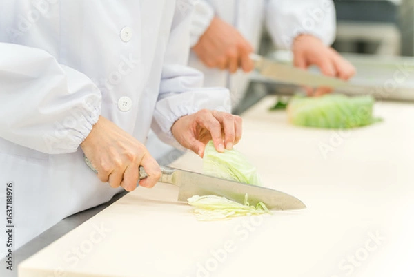 Fototapeta 食品加工場で働くキャベツを切るスタッフの手元
