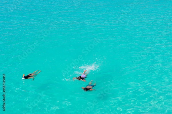 Obraz Three people snorkeling in the crystal-clear turquoise waters of the Caribbean, in Curaçao, conveying leisure, adventure, and connection with nature. Concept of tropical vacations and exclusive touris