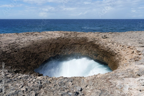 Fototapeta 
Watamula Hole rock formation on the seashore in Curaçao, where the Caribbean waves crash in with force, creating a unique natural spectacle under the blue sky
