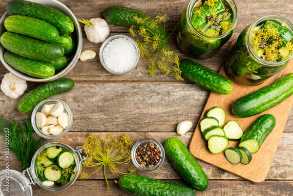 Obraz Freshly-salted homemade cucumbers in a jar on a wooden background. pickled cucumbers with dill,garlic and pepper.canned cucumbers.cucumbers and dill.Recipe of homemade preservations.fermented veggies.