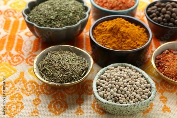 Obraz Many different aromatic spices in bowls on table with cloth, closeup
