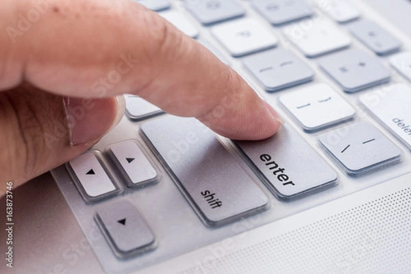 Obraz hand pressing "enter" button on computer