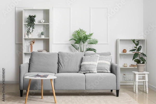 Fototapeta Interior of light living room with sofa, table and shelf units