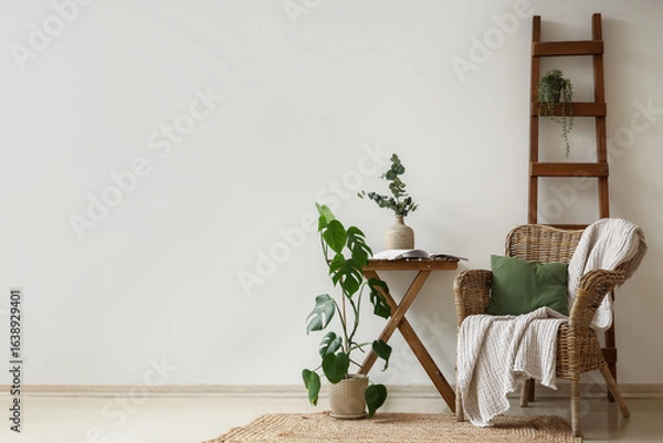 Fototapeta Wicker armchair, ladder and coffee table with houseplants near white wall in room