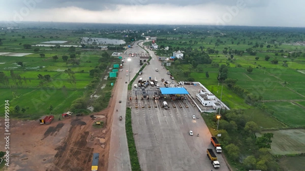 Fototapeta aerial view of highway toll plaza chhattisgarh, drone shot of national highway toll gate india, traffic at toll collection point surrounded by greenery, infrastructure and transportation stock photo. 