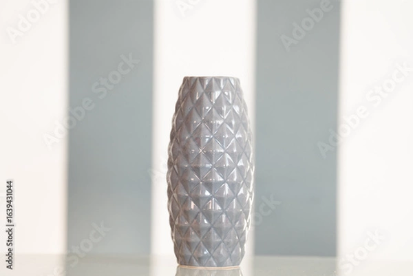Fototapeta Gray ceramic vase on a white and gray background, placed on a kitchen table as a decorative element