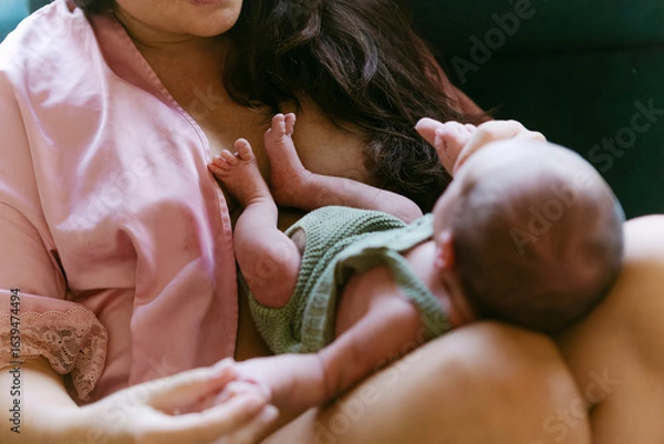 Fototapeta Newborn baby lying on mother’s lap showing bond and connection