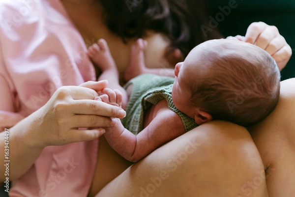 Fototapeta Newborn baby lying on mother’s lap showing bond and connection