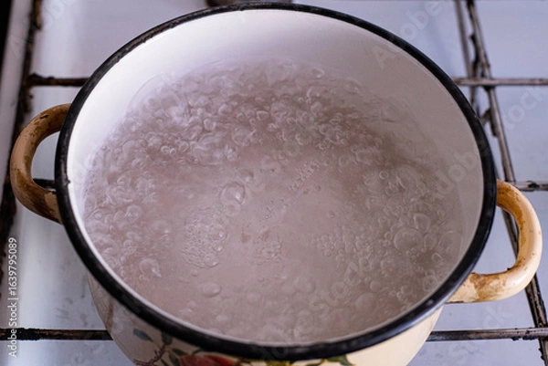 Fototapeta Bubbling water boiling in a vintage pot on a rustic stove, capturing the essence of culinary preparation