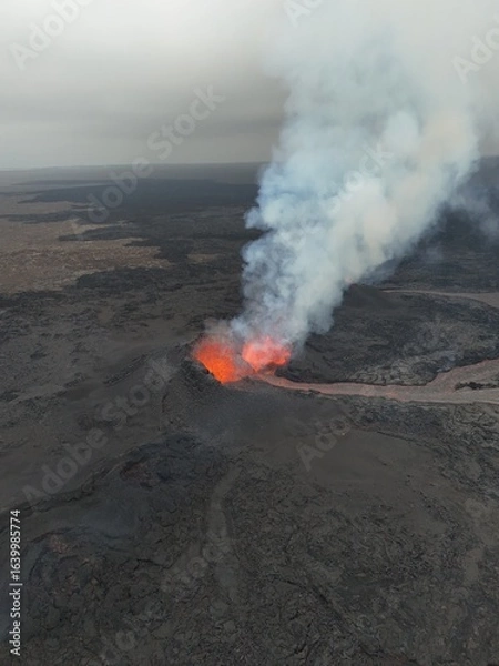 Fototapeta 4K Aerial Drone Footage of an Active Volcanic Eruption with Lava Flow and Smoke over a Rugged Lava Field